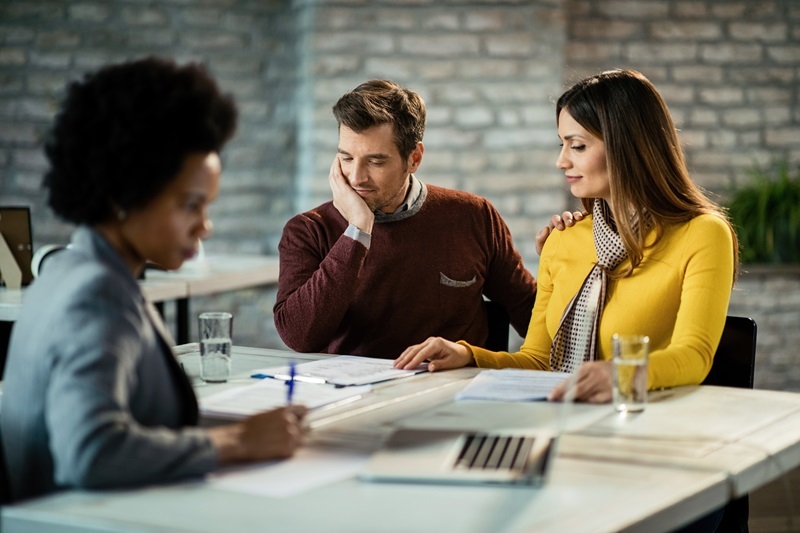 Smiling couple analyzing their business reports on a meeting with insurance agent.